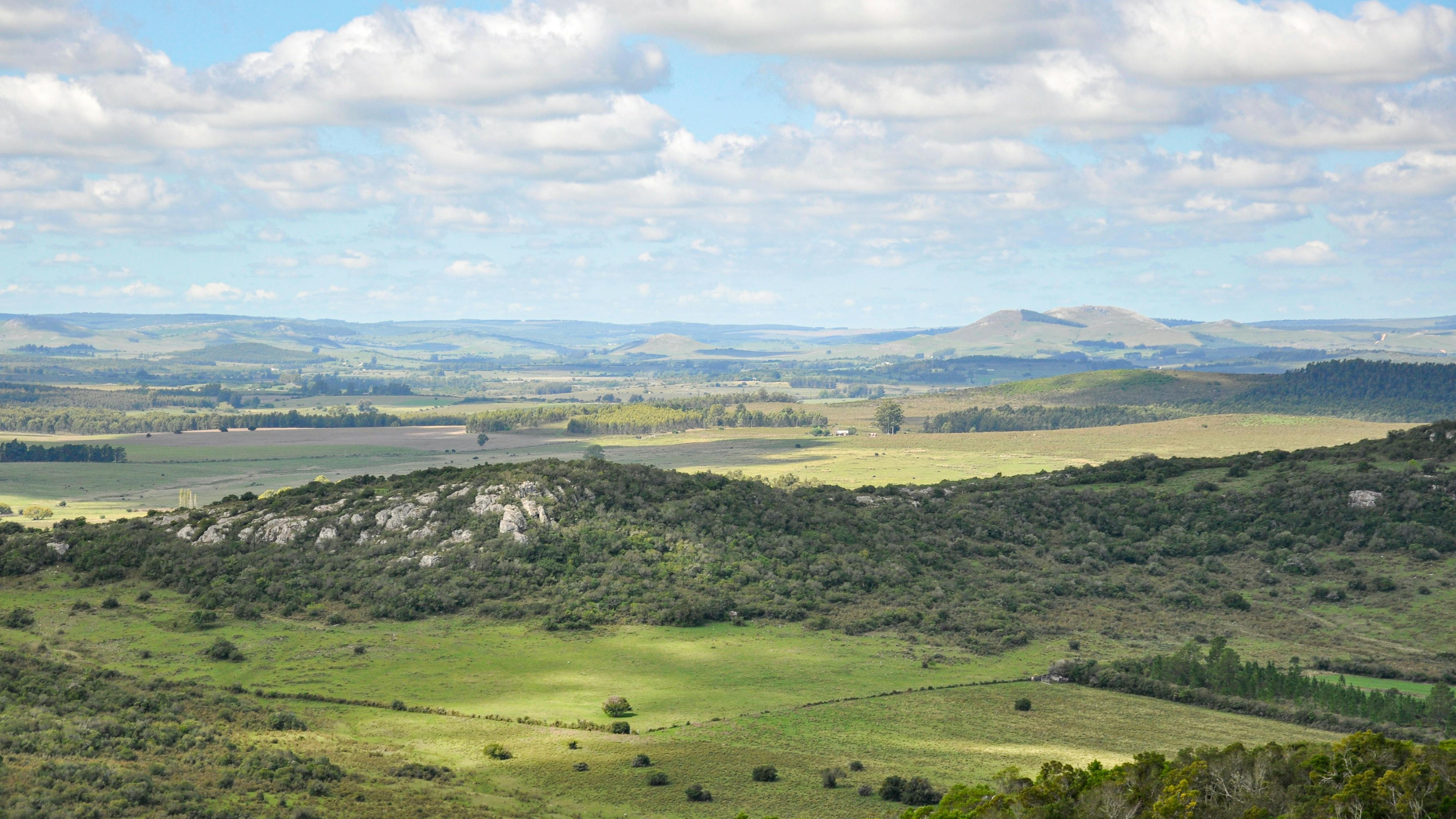 Paisagem de Lavalleja, no Uruguai, com campos e relevo suave sob céu parcialmente nublado.